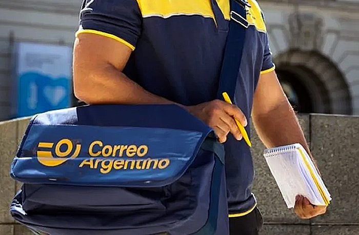 Trabajador postal organizando correspondencia y paquetes en una oficina de correos.