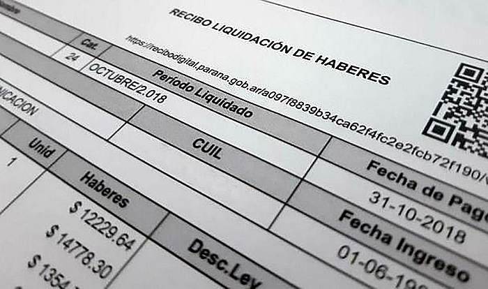 Documento de recibo de sueldo con lupa sobre los detalles de costos laborales
